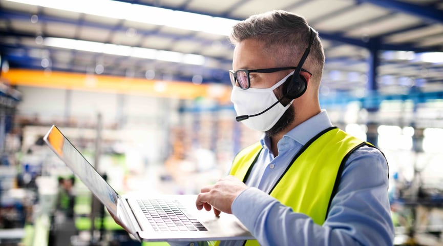 manufacturing worker wearing face mask and holding laptop